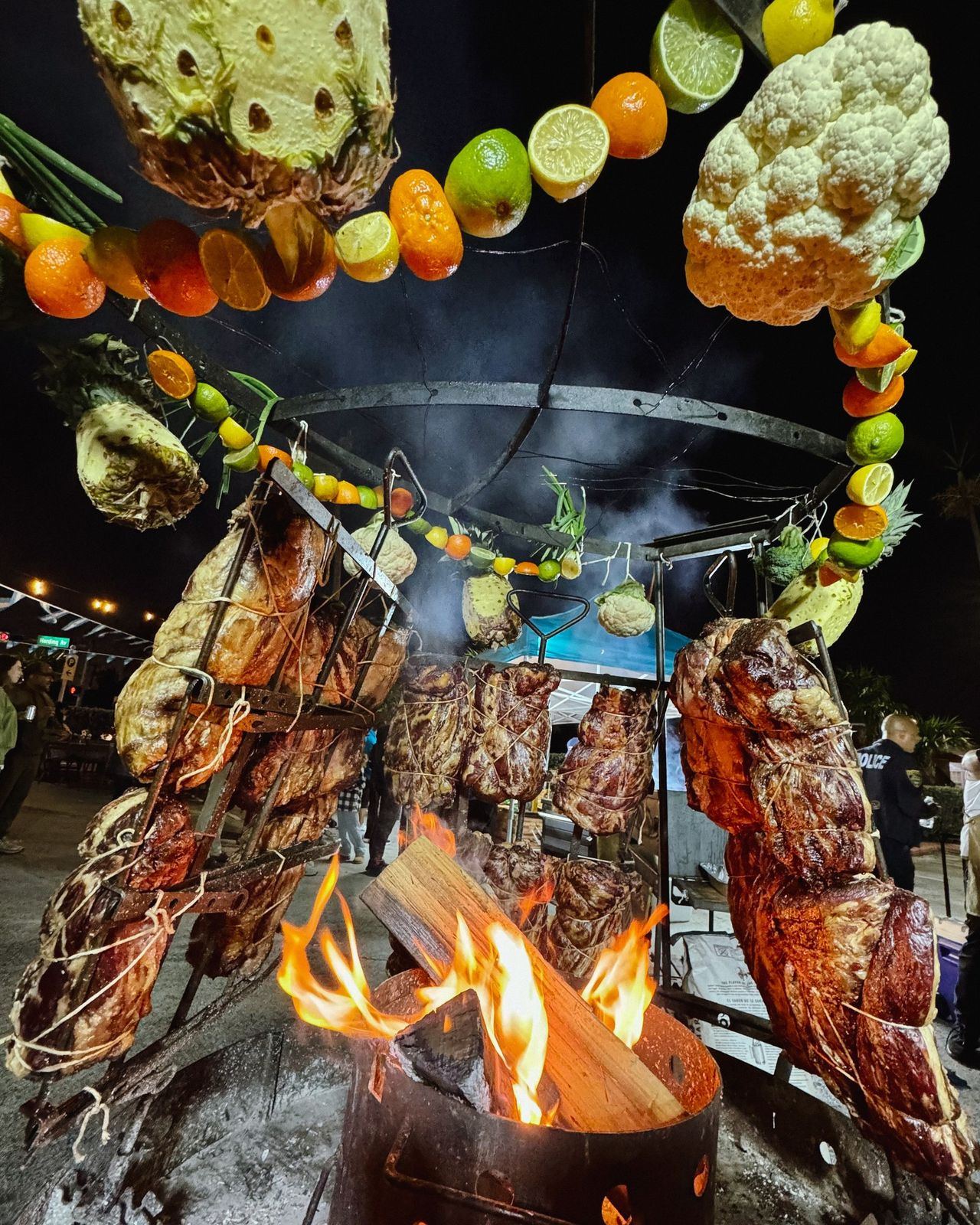 Open-fire asado under a citrus garland