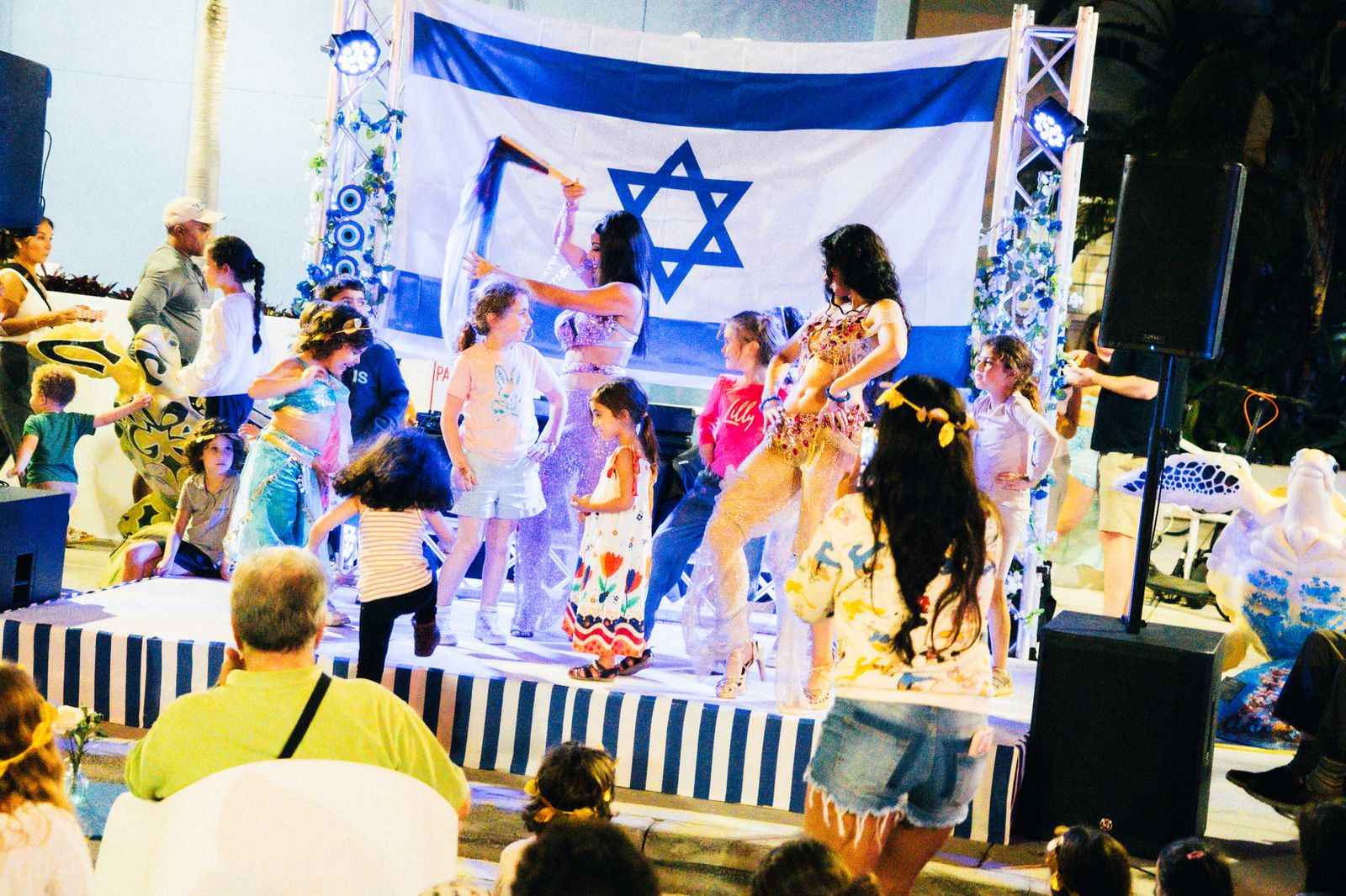 Dancers performing in front of a large flag on the street stage